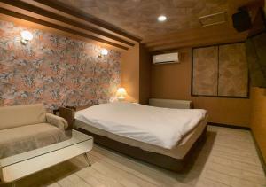 a small bedroom with a bed and a couch at ドンキーズジャングル千葉市店 in Chiba