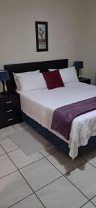 a bedroom with a large bed with white and purple sheets at Sand River Cottages in Hazyview +38 photos