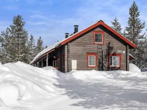 a house with a pile of snow in front of it at Holiday Home Lustola a by Interhome in Luosto