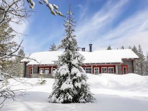 a snow covered christmas tree in front of a house at Holiday Home Lustola a by Interhome in Luosto