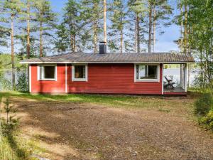 a red house with a tin roof on a dirt road at Holiday Home Mäntylä by Interhome in Nurmes