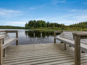 two benches sitting on a dock on a lake at Holiday Home Koivuranta by Interhome in Jämijärvi