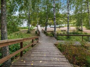 a wooden bridge in a park with trees at Holiday Home Koivuranta by Interhome in Jämijärvi