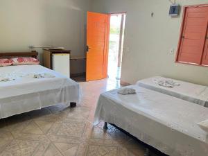 a room with two beds and an orange door at Pousada e Restaurante Cajutuba in Belterra