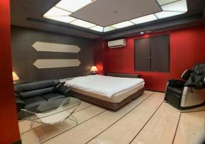 a bedroom with a bed and a couch and a tv at ドンキーズジャングル千葉市店 in Chiba