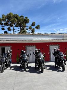 a group of motorcycles parked in front of a red building at Suites CAMINHO DA FÉ in Campos do Jordão