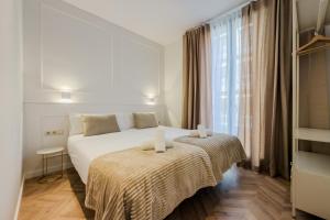 a bedroom with a large white bed and a window at Palau de la Musica Apartments in Barcelona