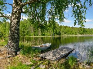 a boat on the shore of a lake with a tree at Holiday Home 21 by Interhome in Varparanta