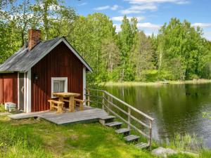 a small cabin with a table on a dock next to a lake at Holiday Home 21 by Interhome in Varparanta