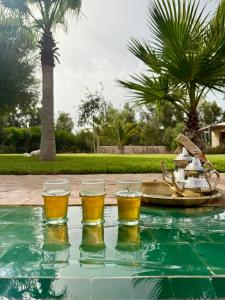 four glasses of beer on a table next to a pool at Maison Flamingo - Boutique hôtel in Essaouira +73 photos
