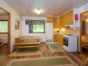 a kitchen with wooden cabinets and a table and a stove at Holiday Home Lomaranta by Interhome in Ruvaslahti