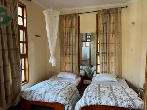 two beds in a room with windows and curtains at The Paradise Inn Kilimanjaro in Moshi +77 photos