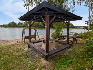 a gazebo with two benches next to a lake at Holiday Home Merimetso 6 by Interhome in Strandby