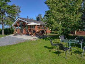 a house with a table and chairs in the grass at Holiday Home Kannelpirtti 1 by Interhome in Puromäki