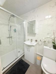 a white bathroom with a shower and a sink at Notting Hill Guest Flat in Ealing