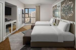 a hotel room with two beds and a desk at Rotana Jabal Omar Makkah in Mecca