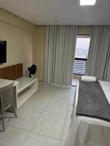 a bedroom with a bed and a table and a window at Flat no Vivence Suites em Palmas in Palmas