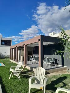 a house with white chairs on the grass at Acacias Mina Clavero in Mina Clavero