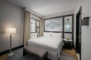 a bedroom with a white bed and a chair at Rotana Jabal Omar Makkah in Mecca