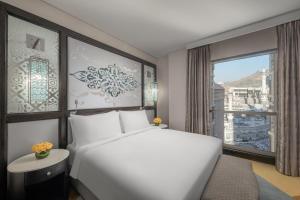 a bedroom with a large white bed and a window at Rotana Jabal Omar Makkah in Mecca