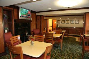 ein Restaurant mit Tischen und Stühlen und einem TV in der Unterkunft Baymont by Wyndham Kalamazoo East in Kalamazoo