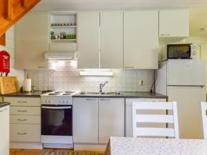 a kitchen with white cabinets and a stove top oven at Holiday Home Kiikkukallio by Interhome in Hankamäki +17 photos