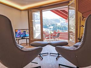 a room with chairs and a balcony with a television at Apartment Eiger Residence Apt-A-425 by Interhome in Wengen +38 photos