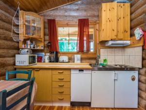 a kitchen in a log cabin with a table and chairs at Holiday Home Lemmenmaja by Interhome in Paatela