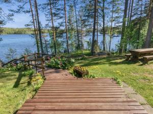 a wooden pathway leading to a lake with a bench at Holiday Home Lehtimaja by Interhome in Tiitanvaara