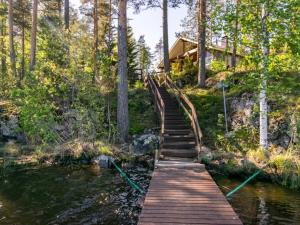 a wooden bridge over a river in front of a house at Holiday Home Lehtimaja by Interhome in Tiitanvaara