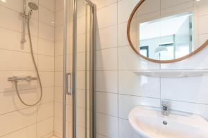 a bathroom with a shower and a sink and a mirror at Utrecht City Apartments - Huizingalaan in Utrecht +27 photos