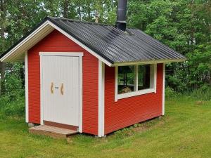 a red and white shed with a dog looking out the window at Holiday Home Laavusranta by Interhome in Kantala +14 photos