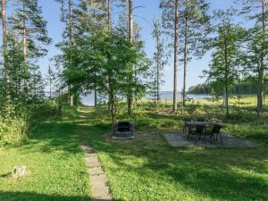 a picnic table and a grill in a field with trees at Holiday Home 6440 by Interhome in Pihlajaniemi