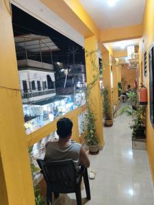 a man sitting in a chair in front of a store at Krishna Guest House in Arambol