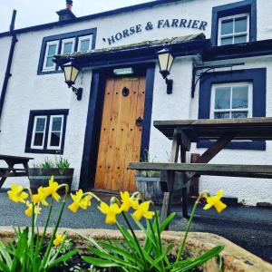 a house and farmer building with yellow flowers in front of it at Horse & Farrier Pub in Dacre +15 photos
