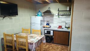 a kitchen with a table and a white refrigerator at Cabañas El Molle in Cavalango
