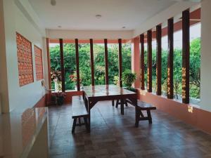 a dining room with a table and benches and windows at Jarens Diner in Silang