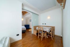a room with a table and chairs and a bedroom at Hotel Erica in Tesero
