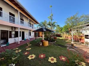 a courtyard of a building with an umbrella and flowers at Recanto Aconchego Itapoá in Itapoa