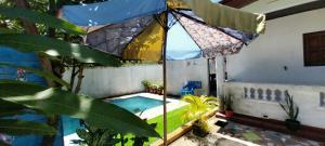 an umbrella over a swimming pool with plants at Maison d'hôtes Villa Mont du Pèlerin à Toamasina Madagascar in Toamasina