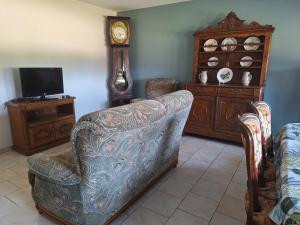 a living room with a couch and a clock at Au gîte de Marcelle in Labergement-lès-Seurre