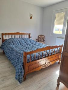 a bedroom with a wooden bed with a blue comforter at Au gîte de Marcelle in Labergement-lès-Seurre