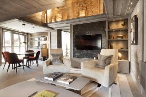 a living room with a table and chairs and a tv at Hotel Le K2 Chogori in Val-d'Isère
