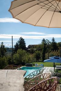 a patio with an umbrella and a swimming pool at Tenuta Dei Vicini - Luxury Apartments in San Marzano Oliveto