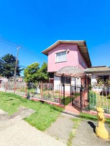 a yellow fire hydrant in front of a pink house at Hospedaje Luna in Valdivia