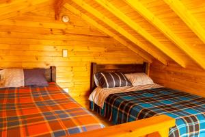 two beds in a log cabin with wooden ceilings at Cabañas Tierra Noble in Nobsa