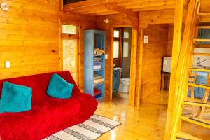 a red couch with two blue pillows in a room at Cabañas Tierra Noble in Nobsa