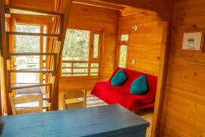 a log cabin with a red couch and blue pillows at Cabañas Tierra Noble in Nobsa