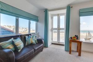 a living room with a brown leather couch and windows at 1 Bed in St. Ives oc-pc716a in St Ives