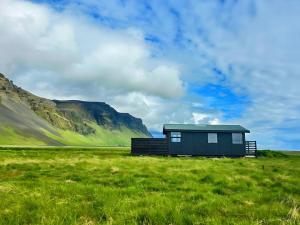 a small house in a field with mountains in the background at Aurora Cabin and Private Jacuzzi in Hvolsvöllur